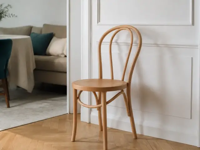 Chaise en bois de hêtre courbé à dossier arrondi, bois clair rosé au grain fin, posée sur un parquet