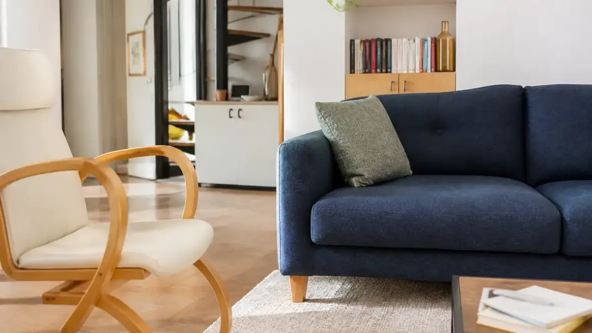 Canapé bleu et fauteuil en bois dans un salon moderne avec meubles de cosyalamaison.fr