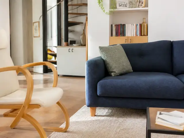 Canapé bleu et fauteuil en bois dans un salon moderne avec meubles de cosyalamaison.fr