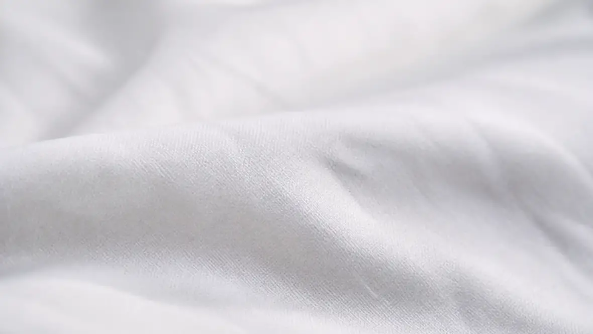 Gros plan sur un drap blanc en percale de coton, tissage fin et serré, surface mate légèrement froissée