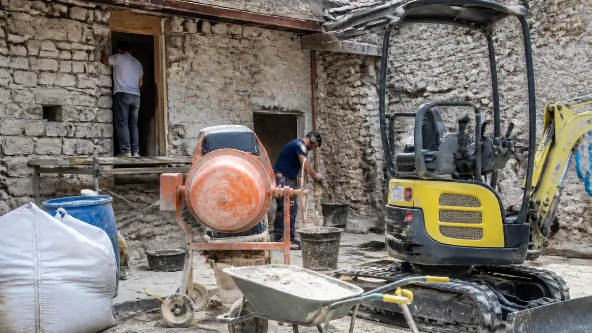Chantier avec pelle mécanique, bétonnière et ouvrier utilisant l'équipement de proxichantier.fr
